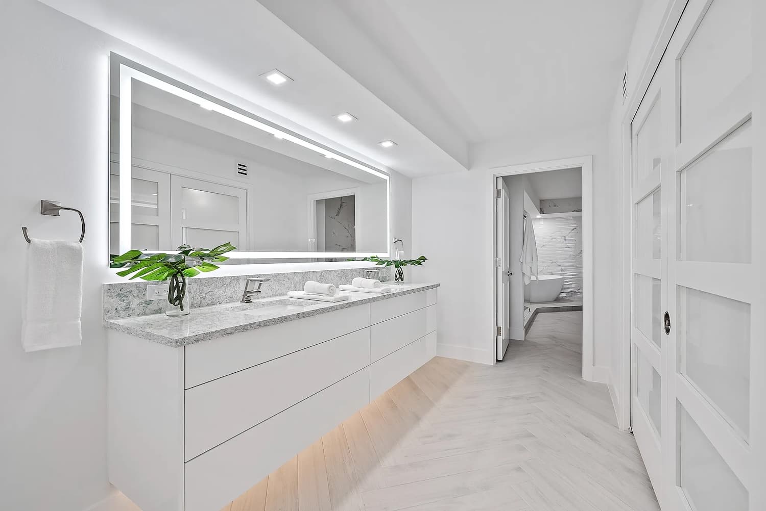 Luxury white bathroom with floating vanity, LED-lit mirror, and marble counters